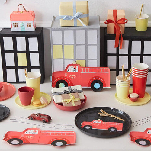 Een feestelijk gedekte tafel met Meri Meri brandweerauto servetten, borden en bekers.