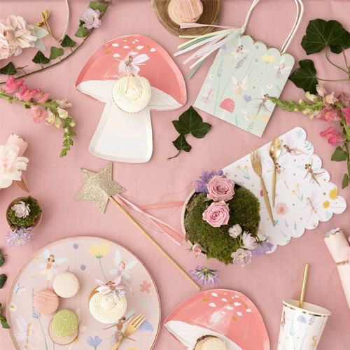 Meri Meri collectie feestartikelen met feeënthema, inclusief borden, bekers en servetten, op een roze ondergrond.
