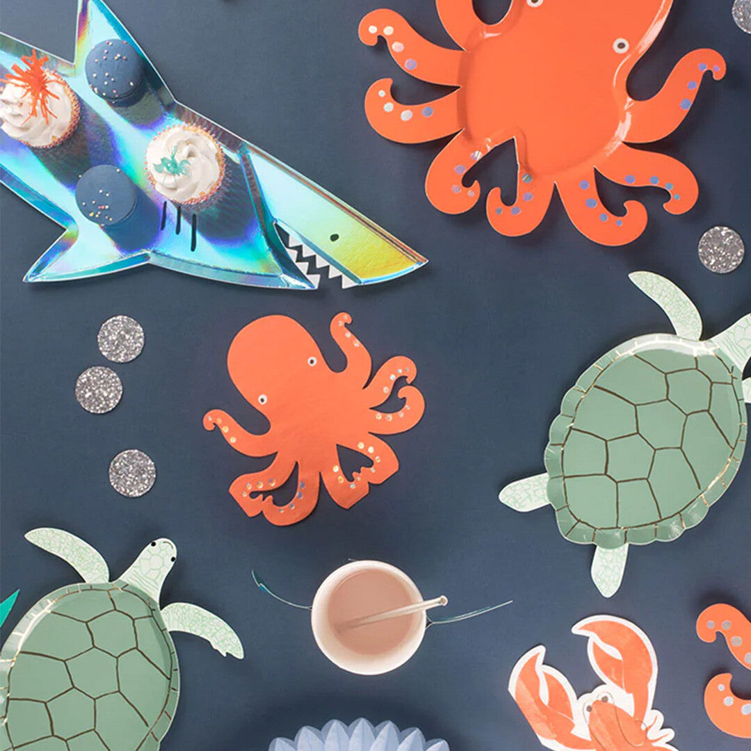 Feestartikelen met onderwaterthema, waaronder een oranje octopus servet, haaienbord en schildpadborden.