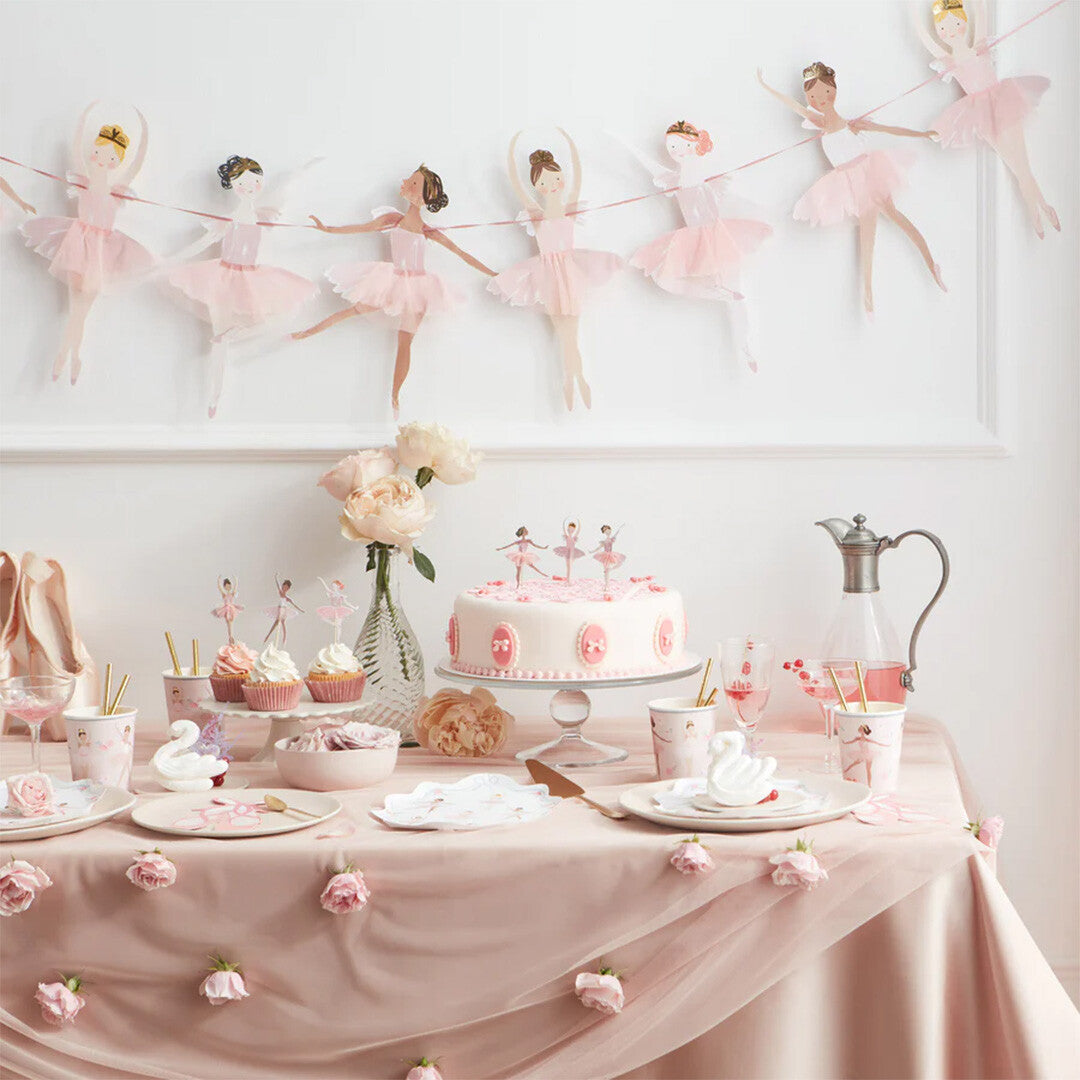 Feestelijk gedekte tafel met roze decoraties en een Meri Meri ballerina slinger op de achtergrond.