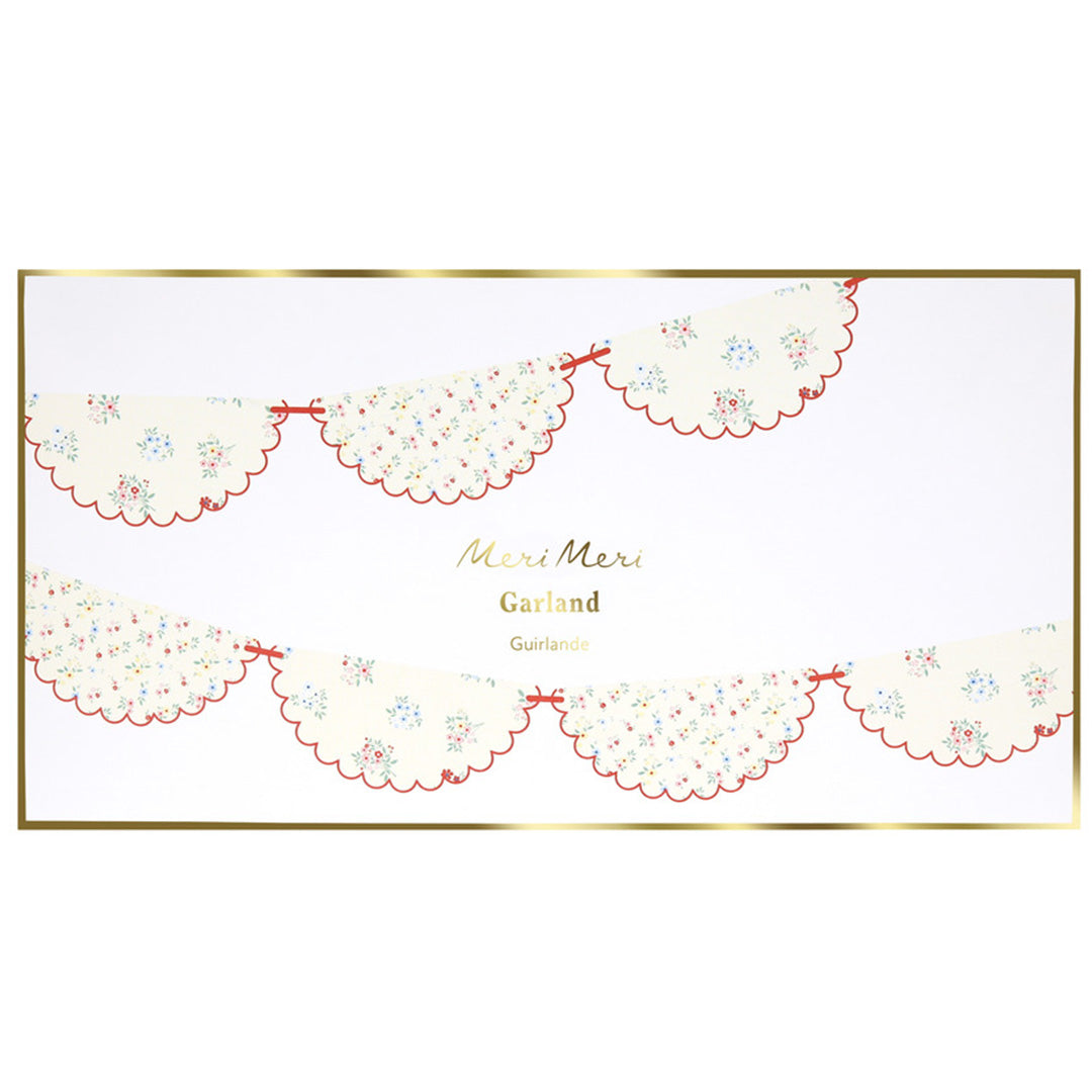 Verpakking van de Meri Meri slinger met een illustratie van de gebloemde vlaggetjes en gouden rand.