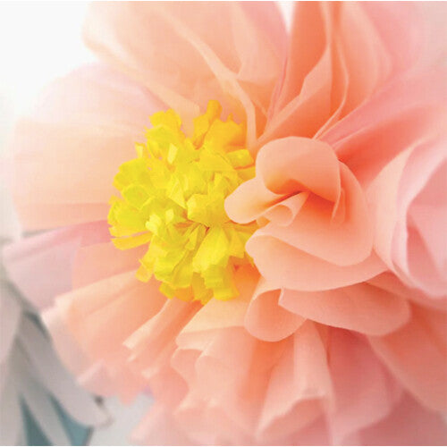 Detail van een roze papieren bloem met geel hart.