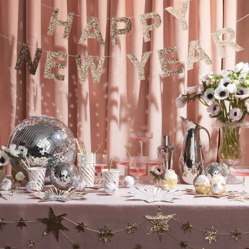 Meri Meri 'Happy New Year' slinger hangt boven een feestelijk gedekte tafel.