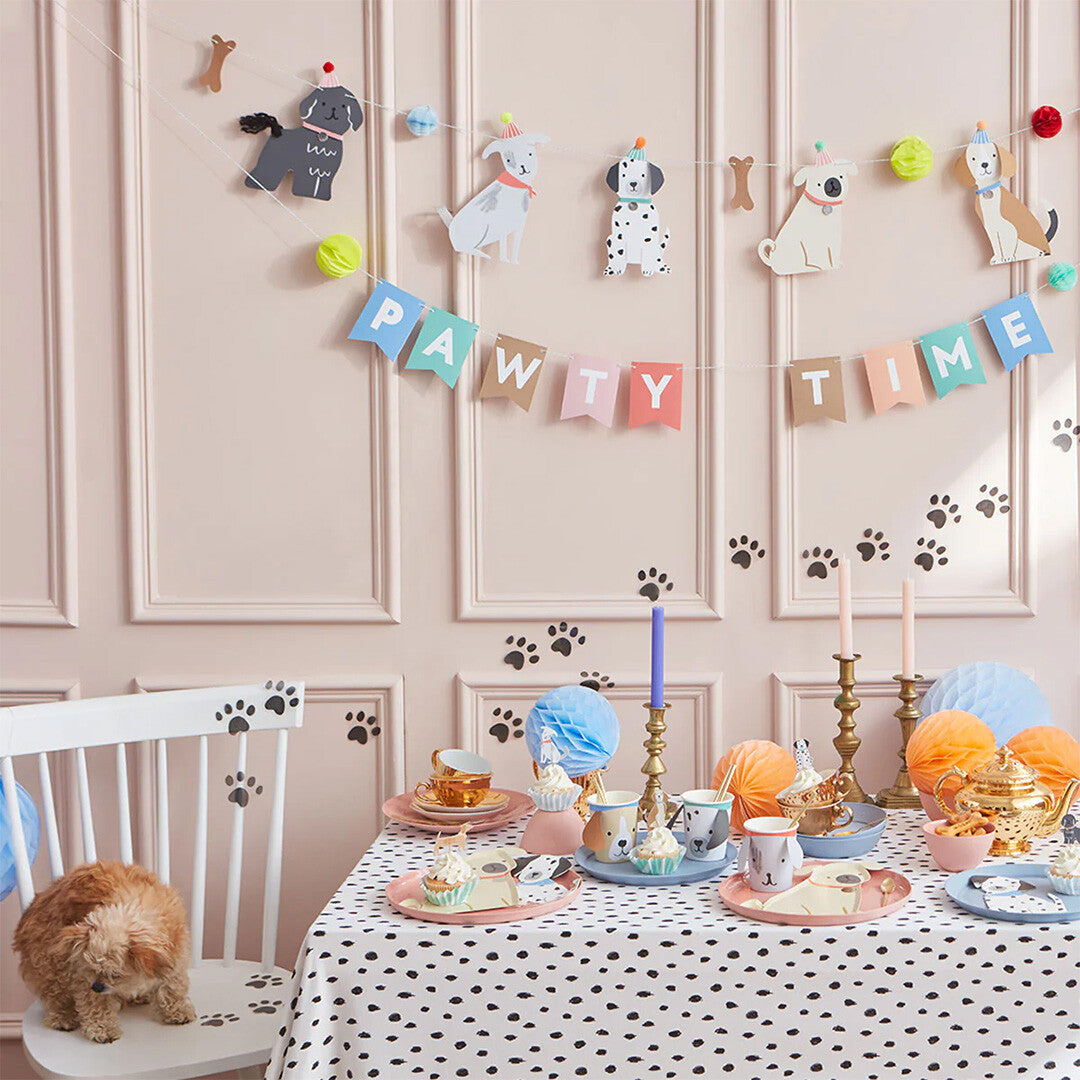 Meri Meri puppy party slinger opgehangen boven een feestelijk gedekte tafel met een kleine hond.