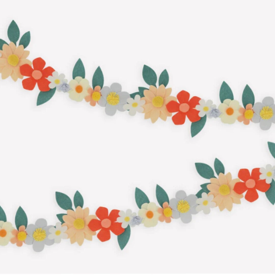 Detail van de vilten bloemenslinger met veelkleurige bloemen en groene bladeren.