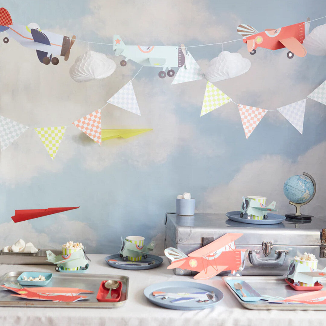 Meri Meri slinger met vliegtuigen en wolken als decoratie op een feesttafel met vliegtuigthema.