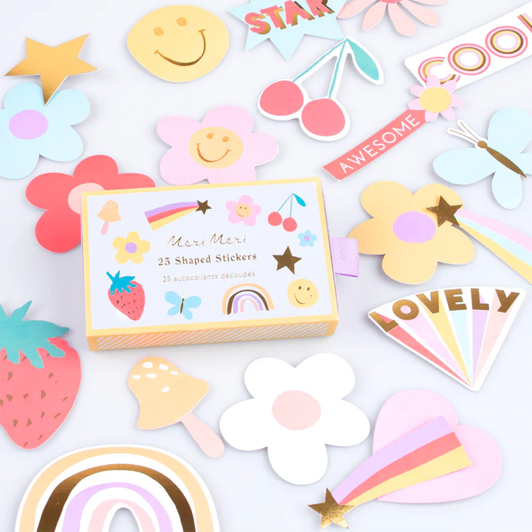 De Meri Meri stickers verpakking omringd door diverse vrolijke stickers met bloemen, regenbogen en een aardbei.