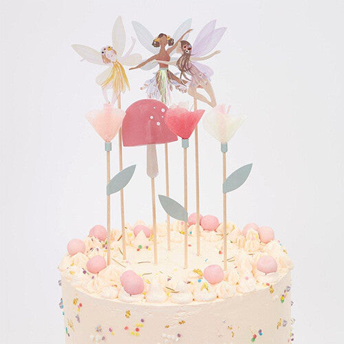 Meri Meri taartversiering met feeën, paddenstoelen en bloemen op een witte verjaardagstaart.
