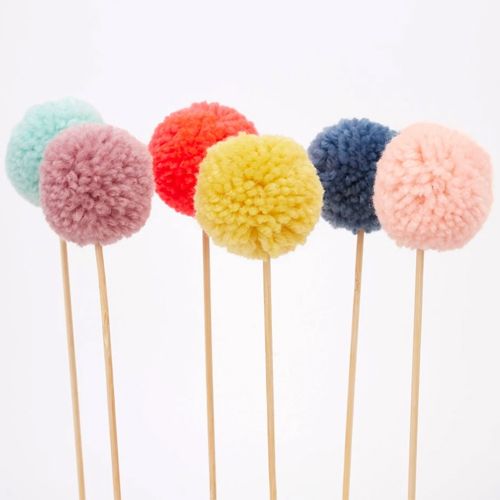 Detail van de Meri Meri pompom taartversiering, zes gekleurde pompoms op stokjes.