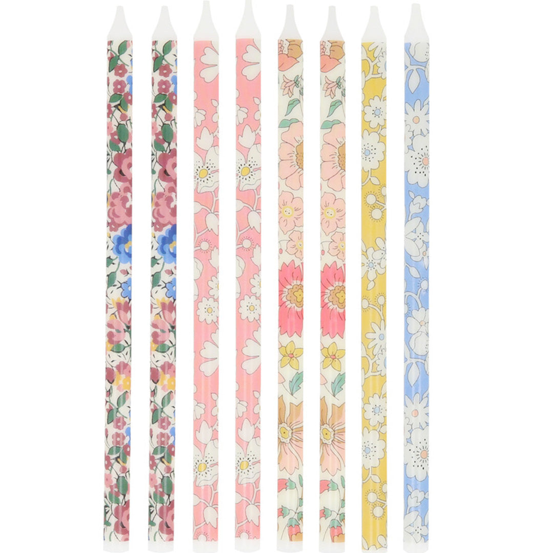 Acht Meri Meri verjaardagskaarsen met veelkleurige bloemmotieven staan rechtop.