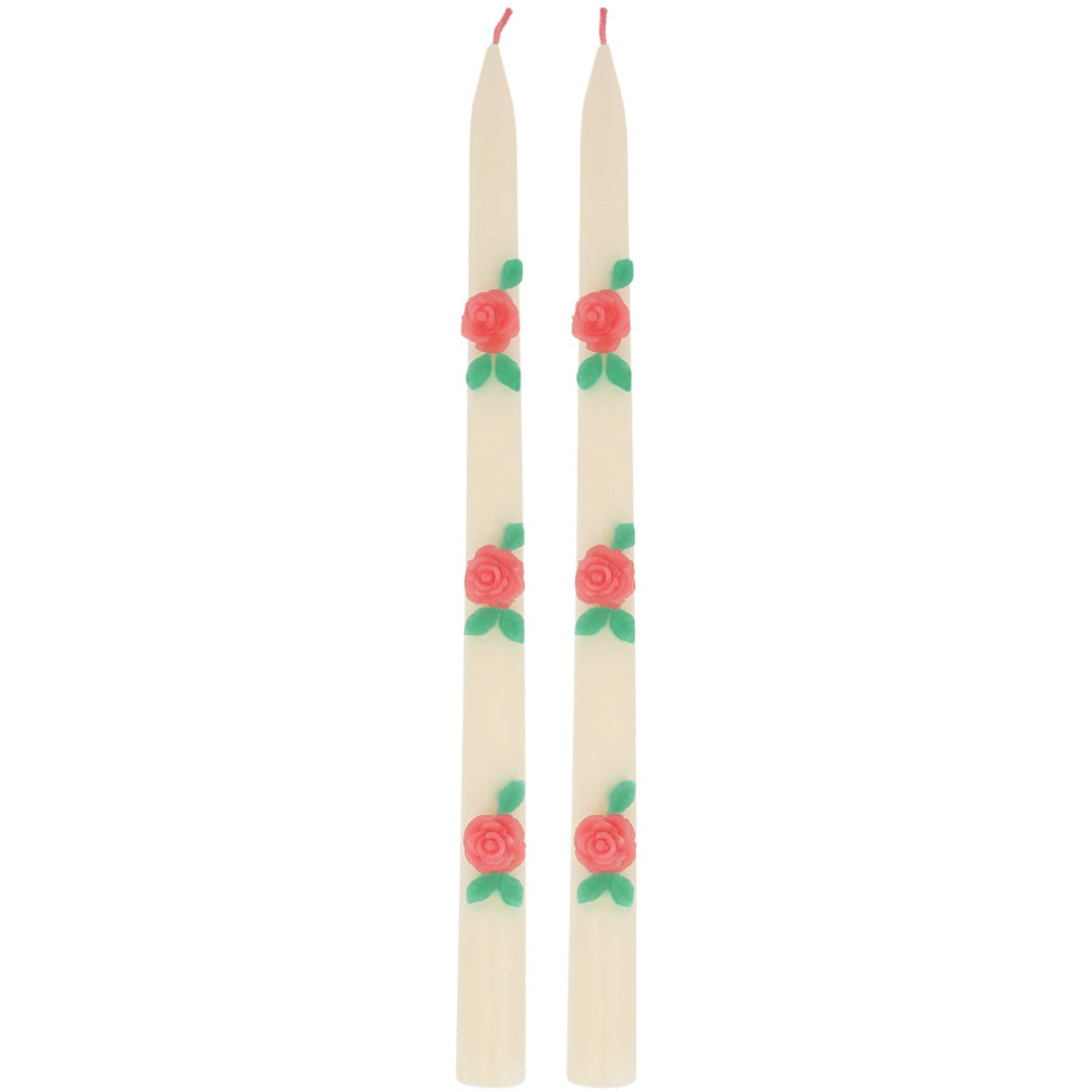 Twee Meri Meri beige conuskaarsen met rode rozen en groene bladeren.