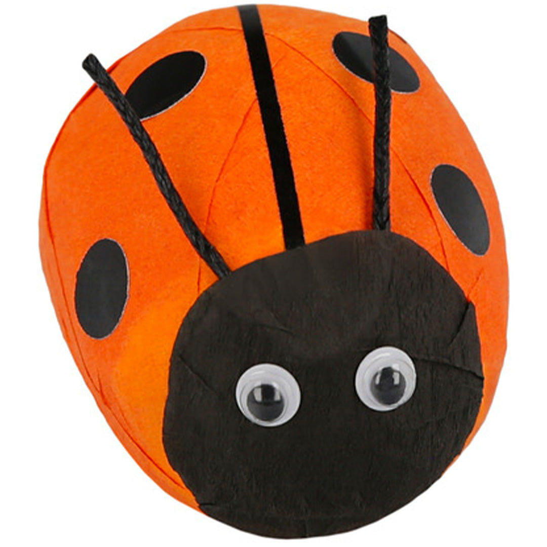 Een close-up van een Meri Meri verrassingsbal in de vorm van een oranje lieveheersbeestje met zwarte stippen en voelsprieten.