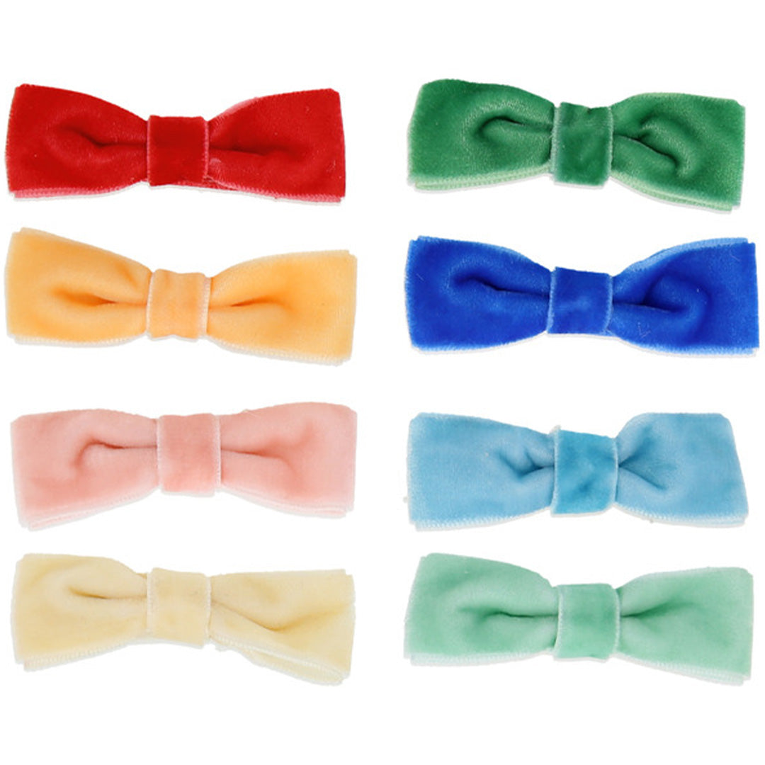 Acht Meri Meri fluwelen haarclips in regenboogkleuren, liggend op een witte achtergrond.