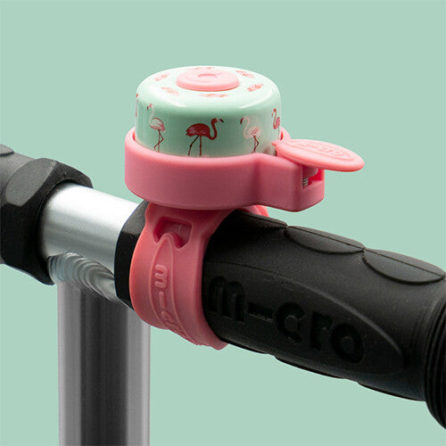 Micro fietsbel met flamingopatroon bevestigd aan een zwart fietsstuur.