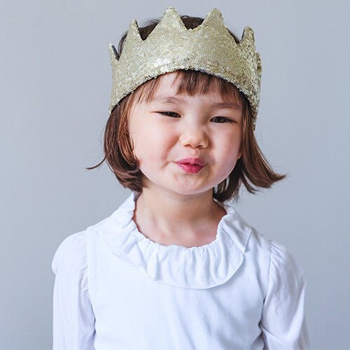 Een kind draagt de mimi & lula gouden pailletten kinderkroon en maakt een kusmondje.