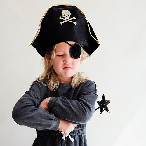 Een kind met de mimi & lula piratenhoed en ooglapje kijkt sip met gekruiste armen en een sterrenstaf.
