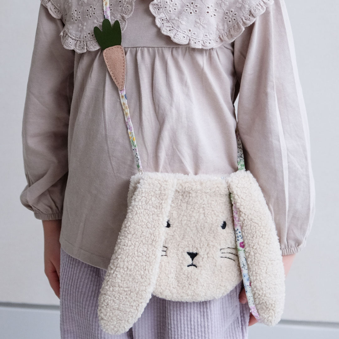 mimi & lula fluffy kinder schoudertasje in de vorm van een konijn, gedragen door een kind met een beige blouse.
