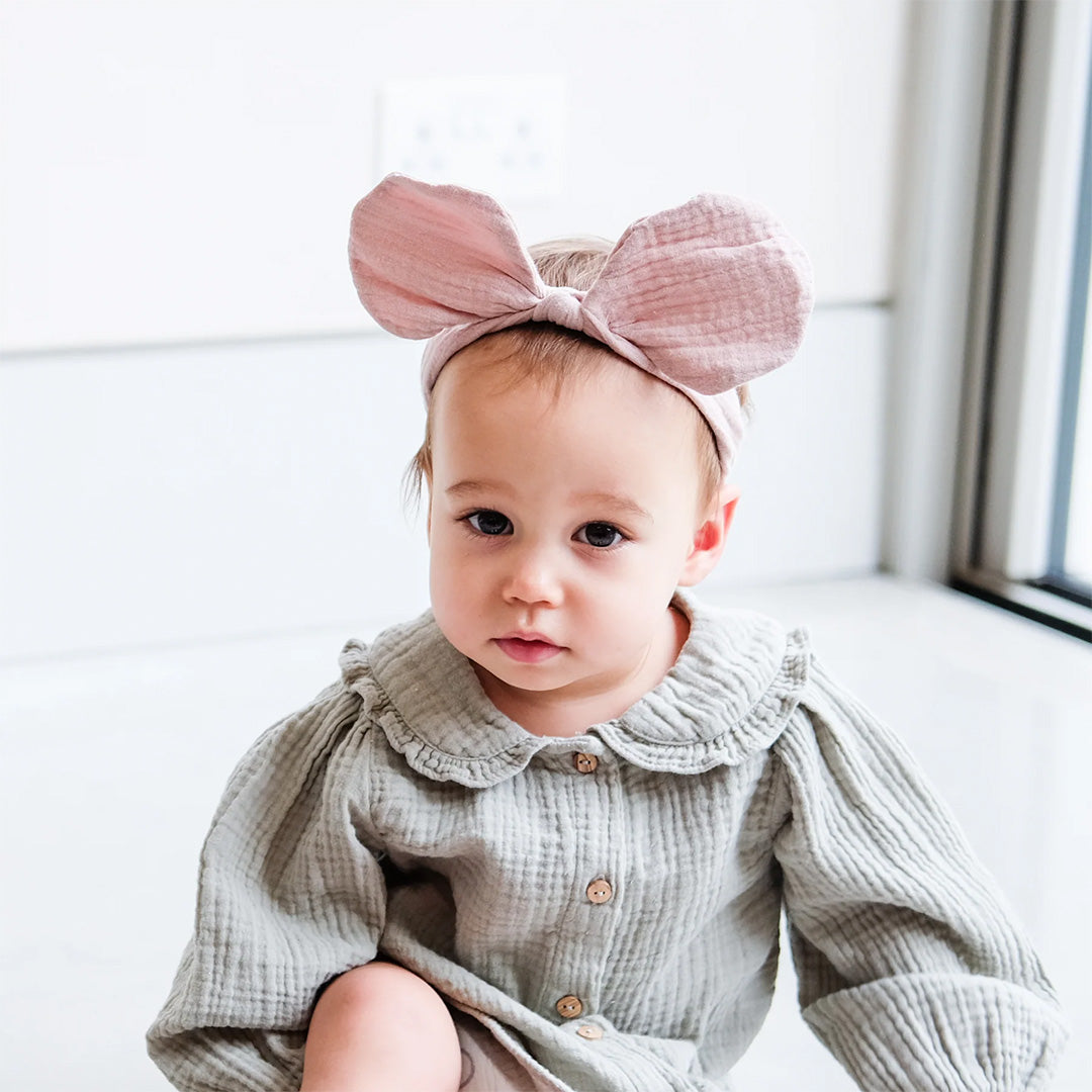 Een baby draagt de roze babyhaarband met grote strik.