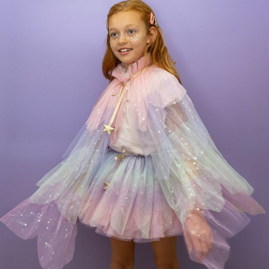 Meisje met rood haar draagt een mimi & lula pastelkleurige verkleedrok en bijpassende cape met glittersterren.