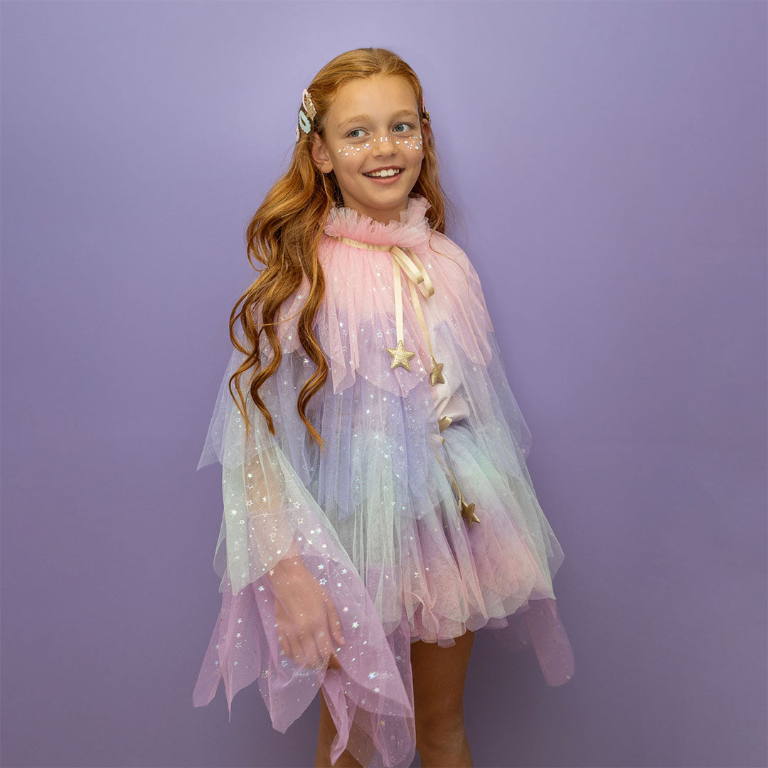 Meisje met rood haar draagt een mimi & lula pastelkleurige verkleedcape met glittersterren.