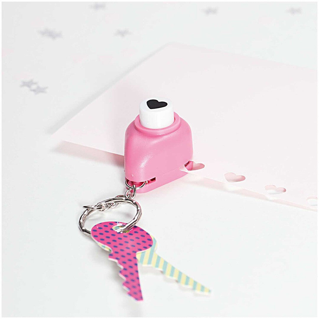 Roze mini perforator sleutelhanger die hartjes ponst in een roze vel papier, met een decoratieve sleutel aan de ring.