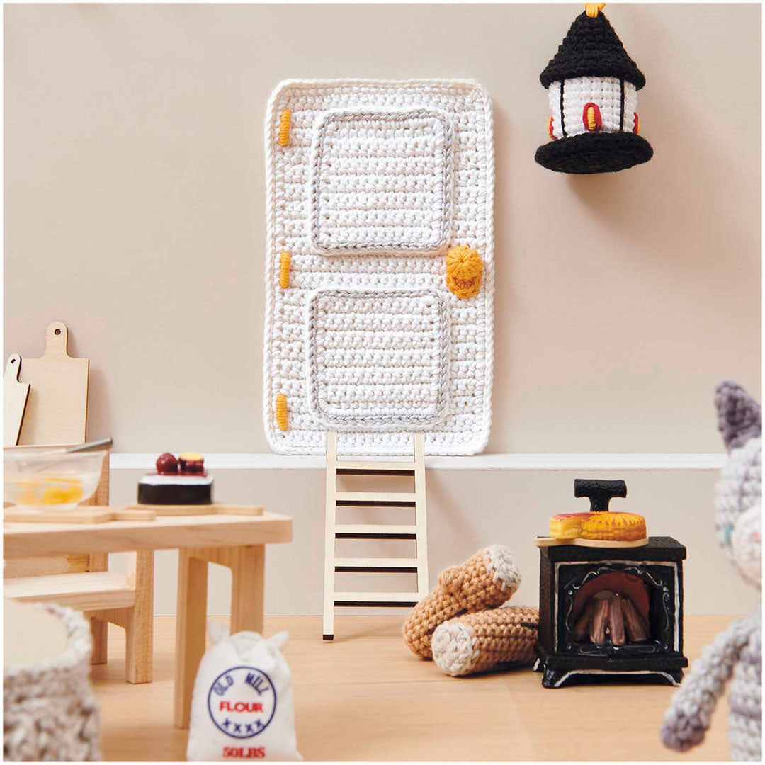 Miniatuur haard met een klein gebakje erop, in een poppenhuissetting met andere meubels en accessoires.