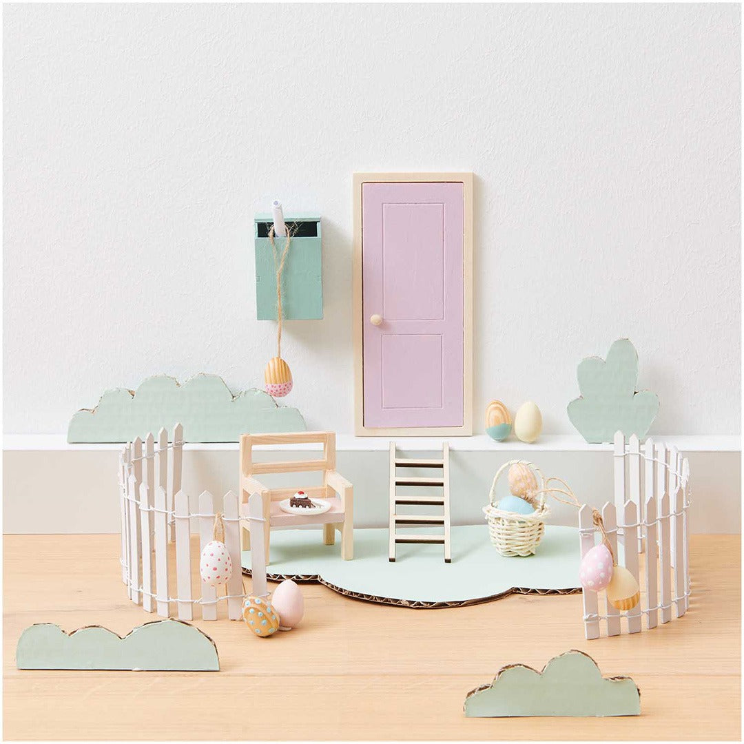 Miniatuur houten stoel in een poppenhuis tuinsetting met roze deur en paaseieren.