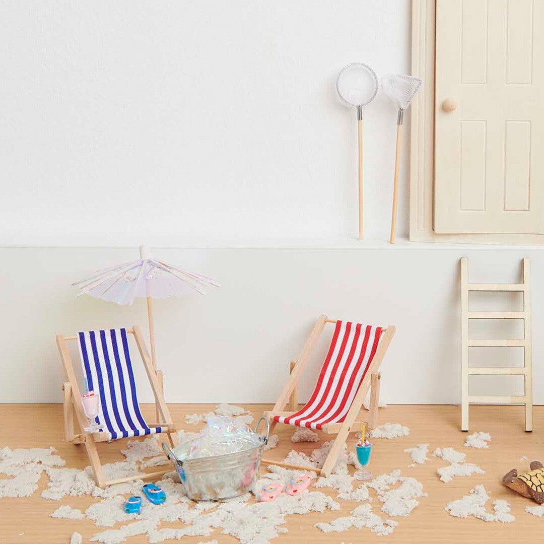 Miniatuur strandscène met twee gestreepte strandstoelen, een parasol en diverse strandaccessoires.