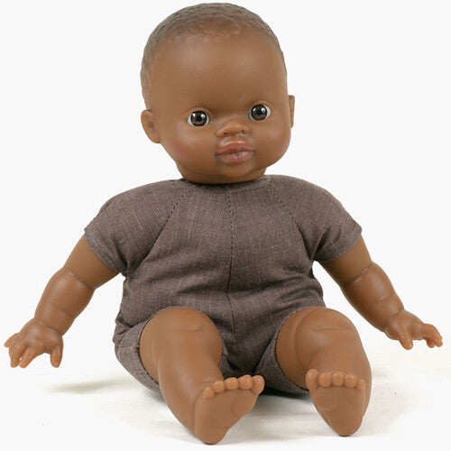 Paola Reina babypop met donkere huidskleur en bruine romper, zittend.