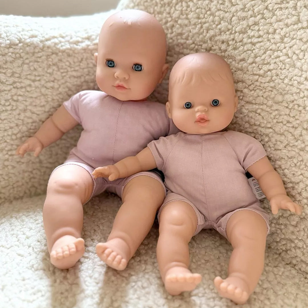 Twee minikane babypoppen met open ogen en roze pakjes zitten naast elkaar.
