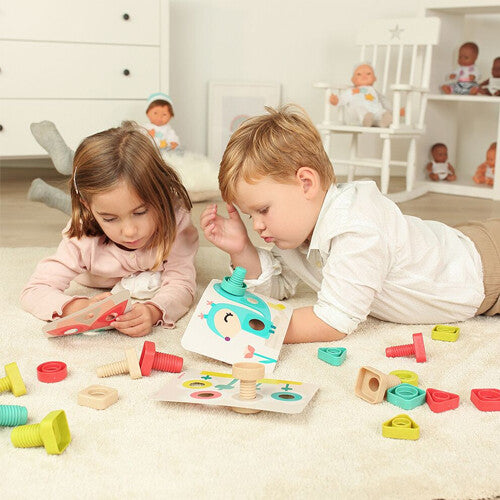 Twee kinderen liggen op de grond en spelen met de miniland knutselset bouten en moeren en kaarten met figuren.