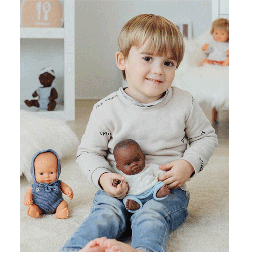 Jonge jongen speelt met een Miniland pop die de gebreide blauw-witte poppenkleding draagt.