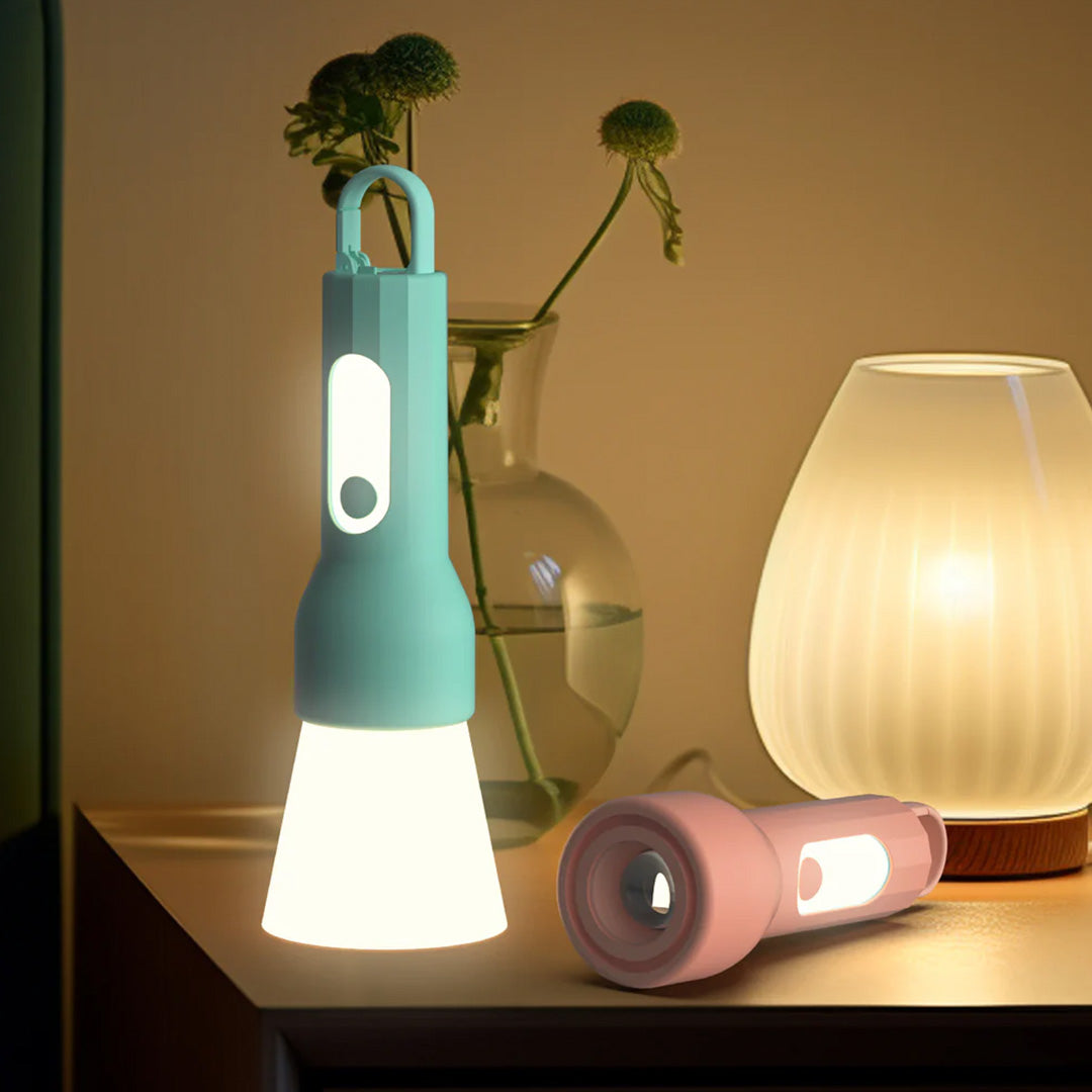 Twee mob Glowy zaklampen, een lichtblauwe staand als lamp en een roze liggend, op een nachtkastje.
