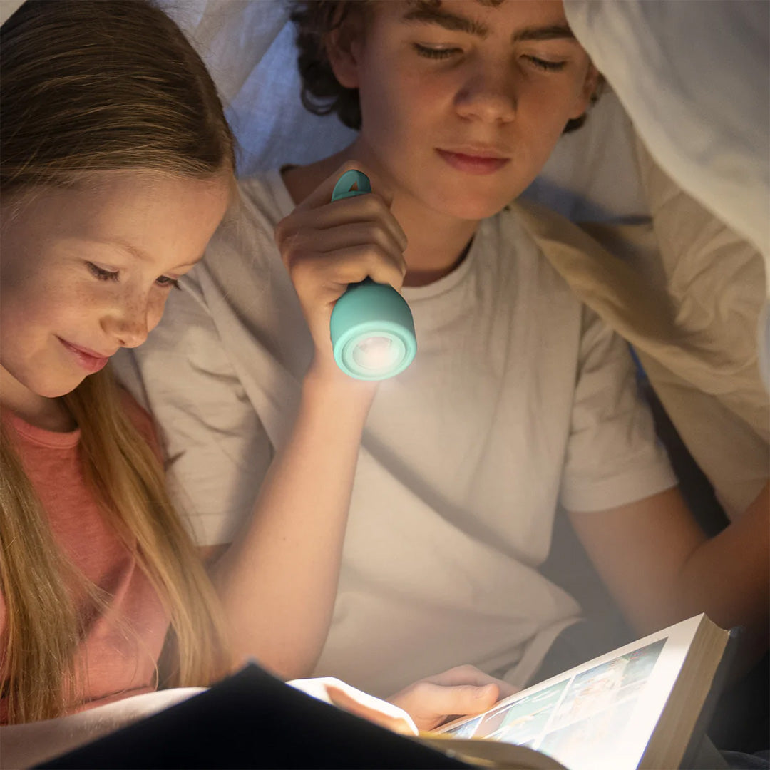 Twee kinderen lezen onder een deken met een mob zaklamp die licht geeft op hun boek.