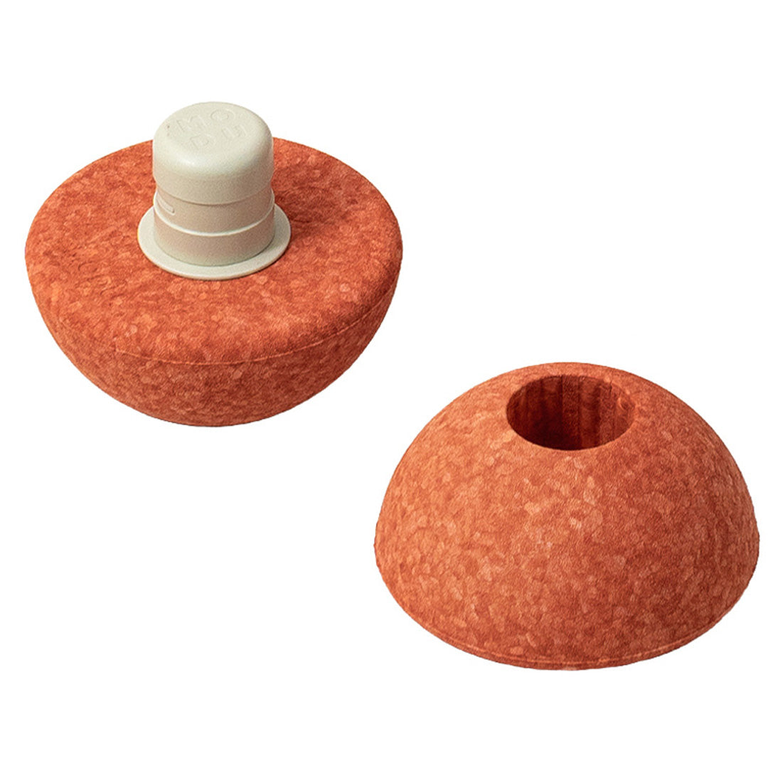 Twee onderdelen van de modu foam bal: een halve bal in burnt orange met een witte connector en een halve bal in burnt orange met een gat.