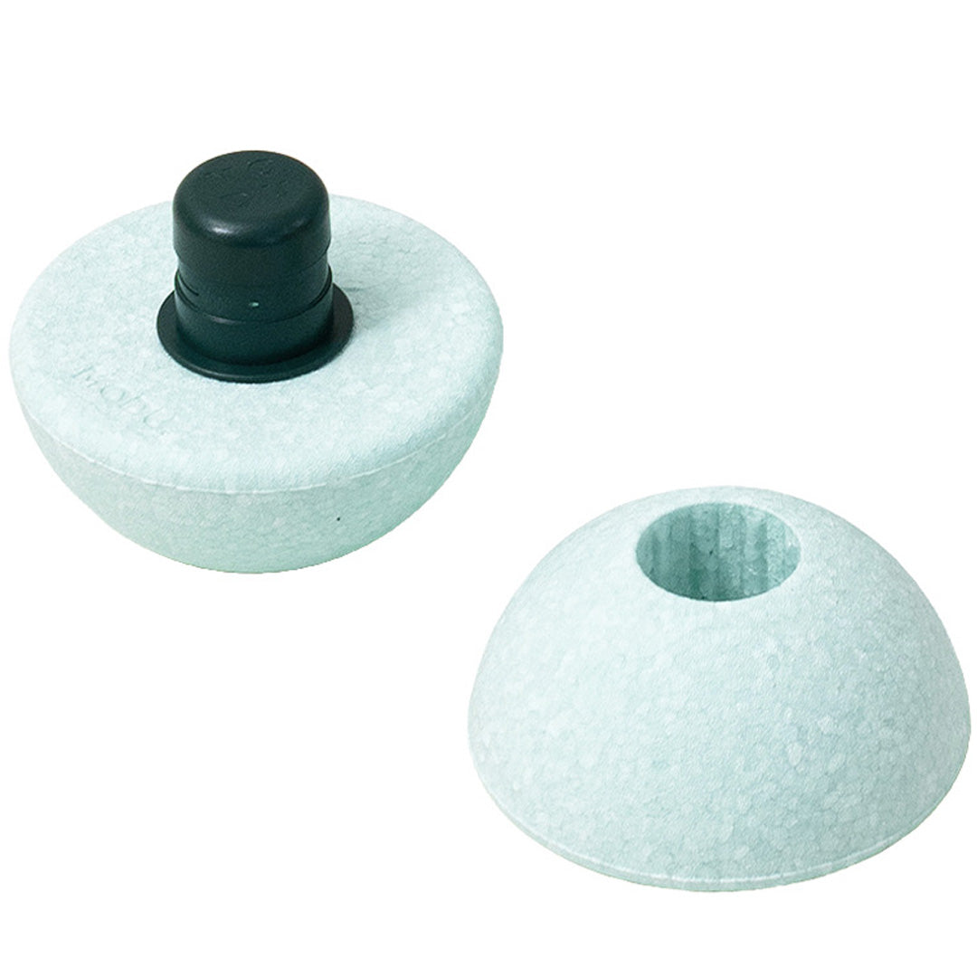 Twee losse onderdelen van de Modu foam bal in ocean mint, waarvan één met een zwarte plug.