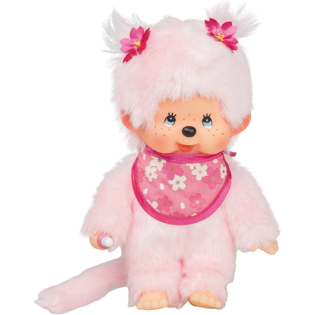 Monchhichi pluchen pop meisje met roze bloemen en een gebloemd slabbetje, schuin van voren.