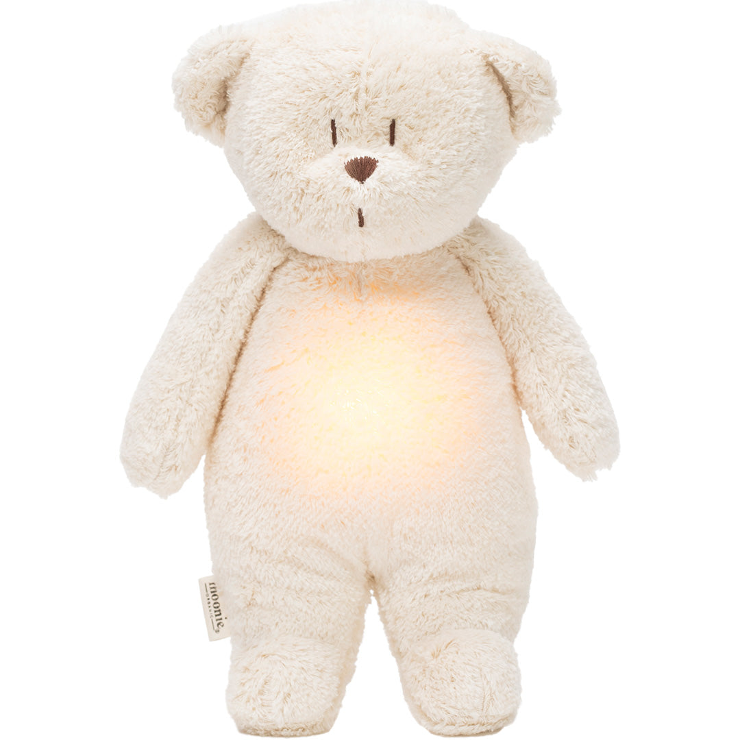 moonie knuffelbeer met nachtlamp, staand met een warme gloed op de buik.
