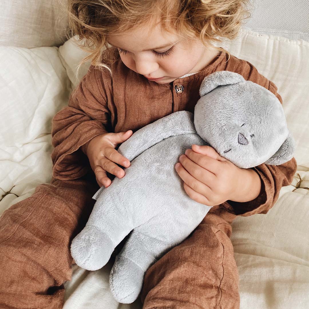 Een kind knuffelt de grijze moonie knuffelbeer.
