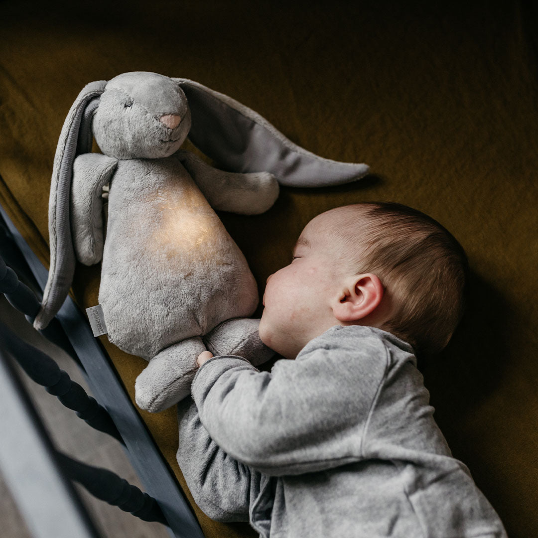 Slapende baby knuffelt het moonie konijn met lichtgevende buik.