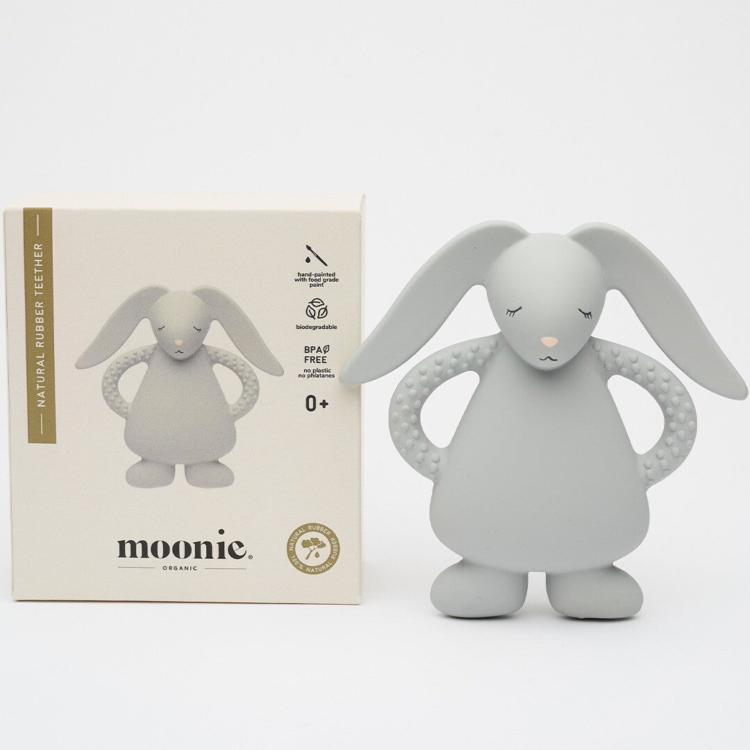 De moonie grijze konijnenbijtring ligt naast de witte verpakking met merklogo en productinformatie.