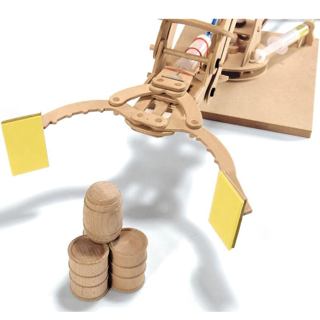 Detail van de grijper van de moses. houten hydraulische robotarm boven drie kleine houten tonnetjes.