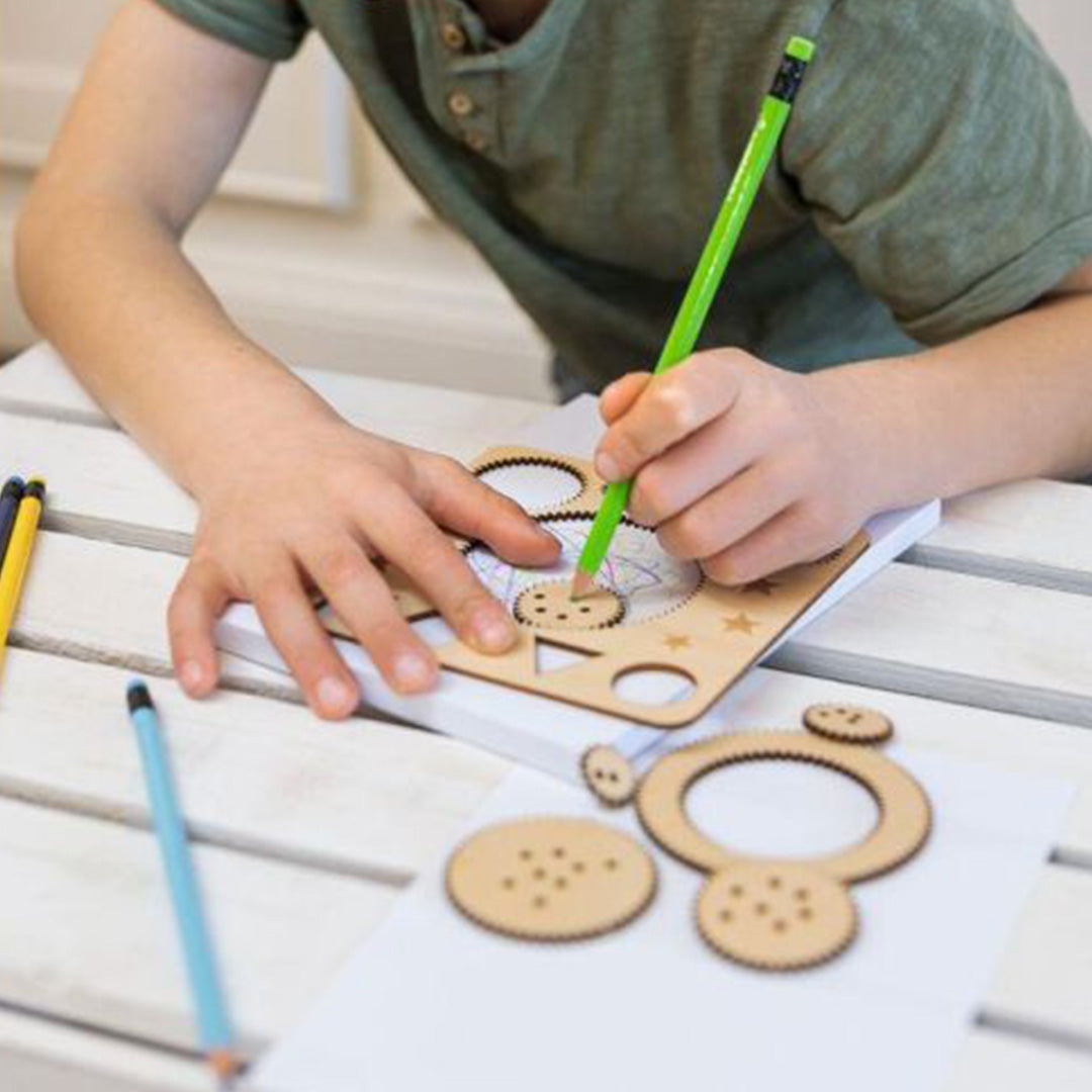 Een kind tekent met een groene potlood en de moses. houten spirograaf set op een wit vel papier.
