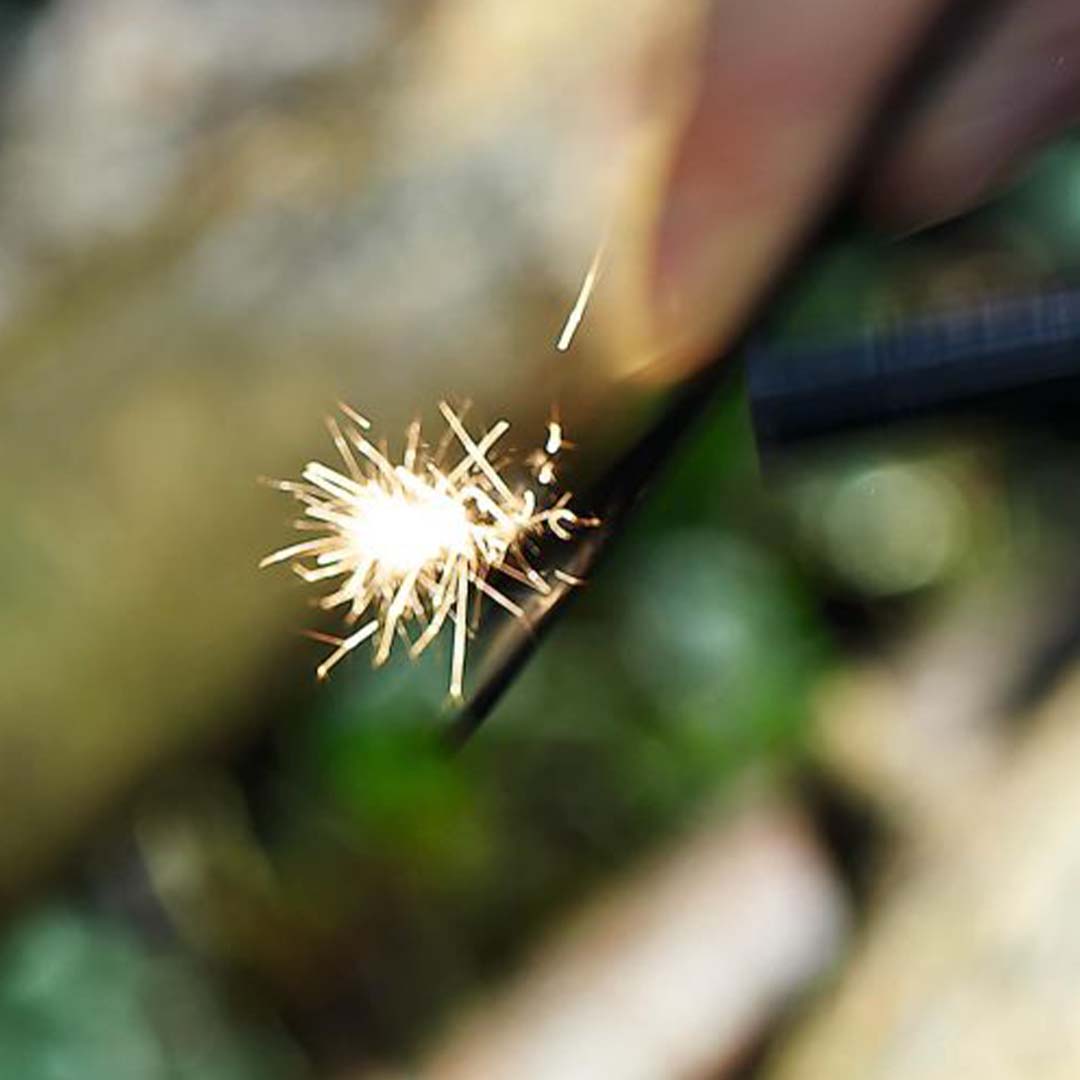 Vonken vliegen van een vuurstarter die wordt gebruikt in een natuurlijke omgeving.