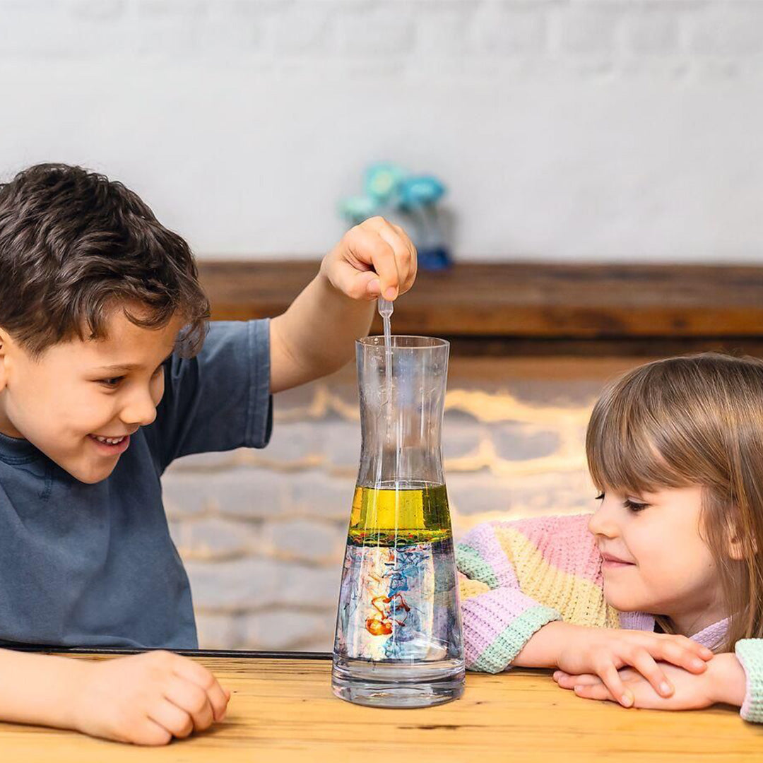 Twee kinderen doen een experiment met een glazen fles gevuld met olie en water, waarbij de jongen een druppelaar gebruikt.