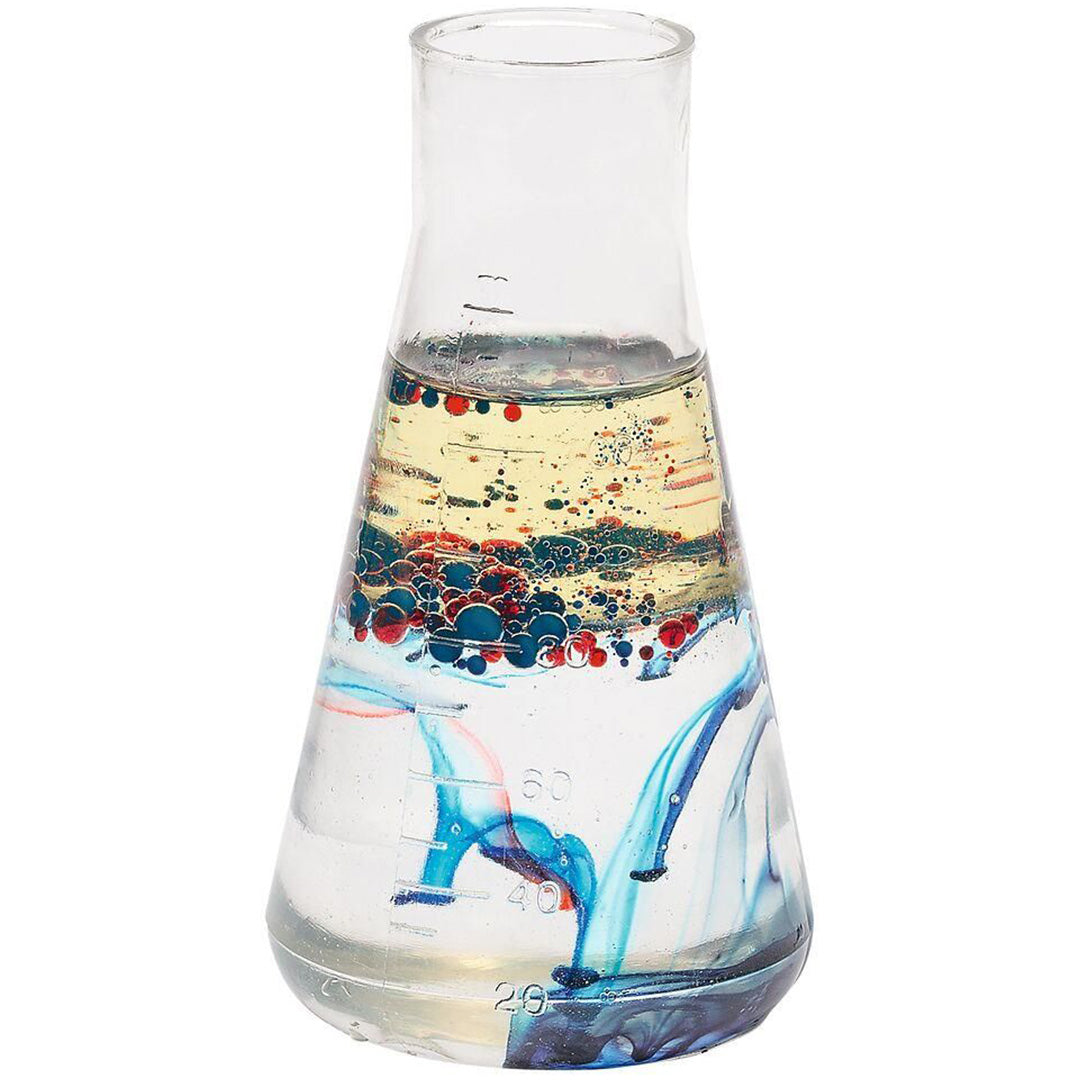Een erlenmeyer gevuld met gele olie en water, waarin rode en blauwe kleurdruppels zinken en zich verspreiden.