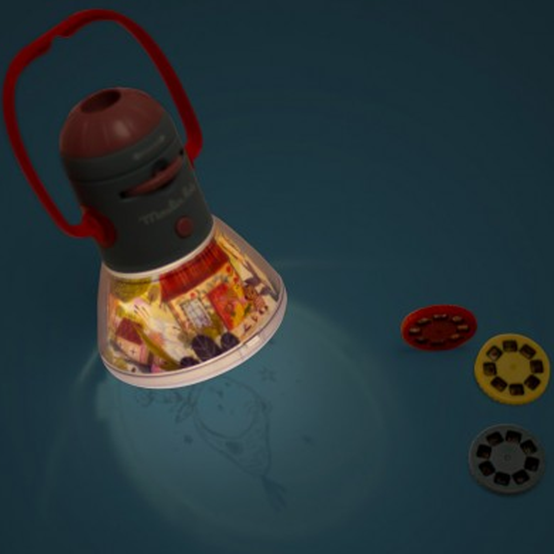 Moulin Roty projector die een figuur projecteert op een donkere ondergrond, met drie verhalen discs ernaast.