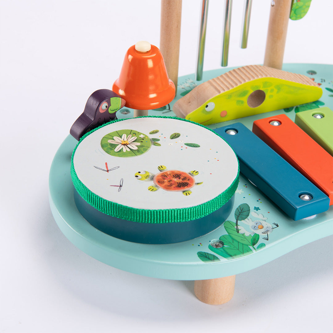Detail van de Moulin Roty muzikale activiteiten tafel met de drum met schildpad en waterlelie, en de oranje bel.