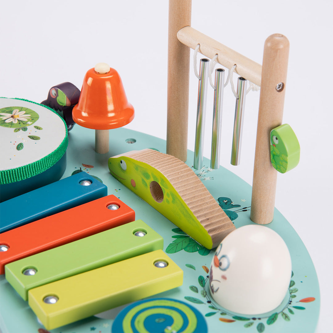 Detail van de Moulin Roty muzikale activiteiten tafel met de metalen klankstaven en de groene houten guiro.