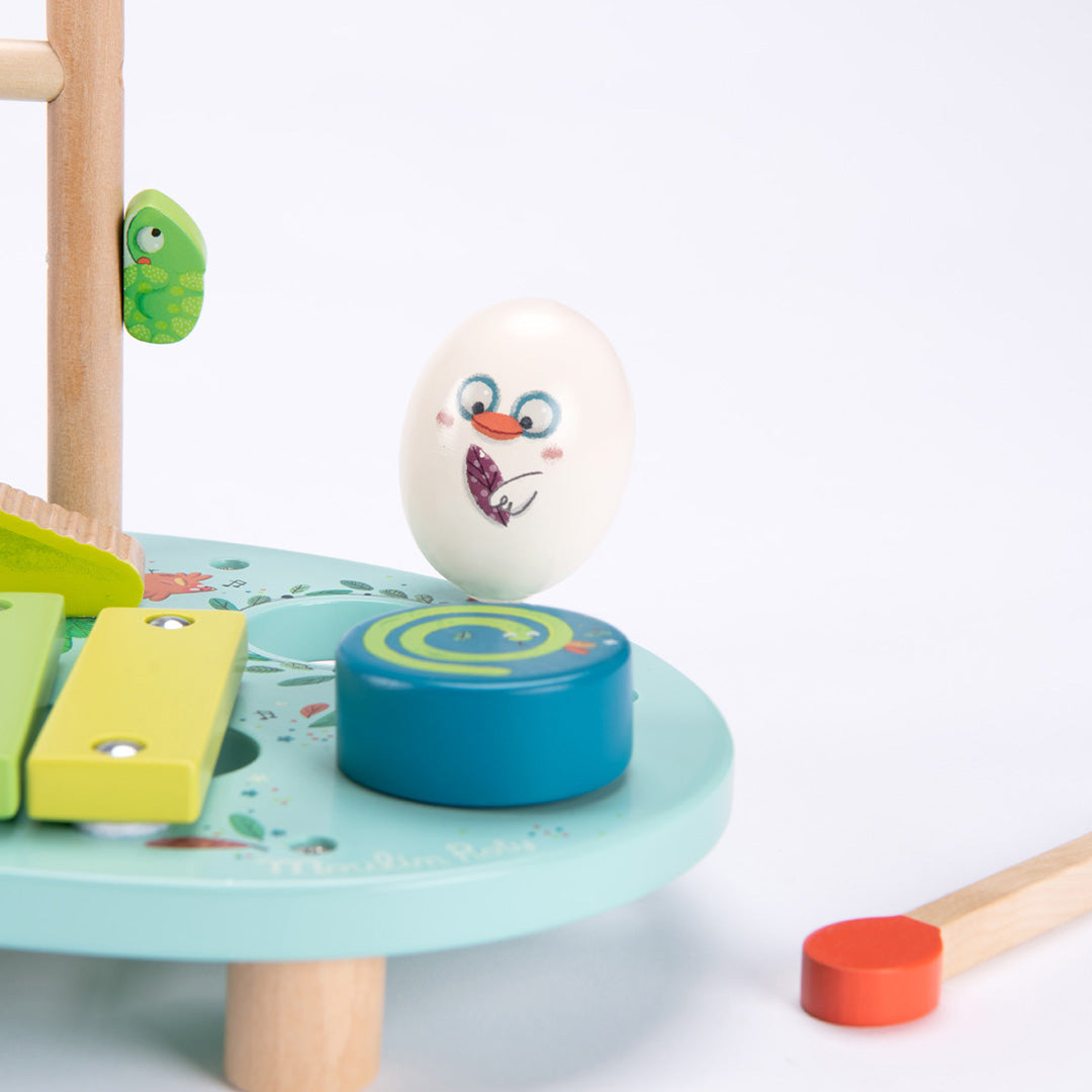 Detail van de Moulin Roty muzikale activiteiten tafel met de witte rammelaar en de blauwe draaischijf.